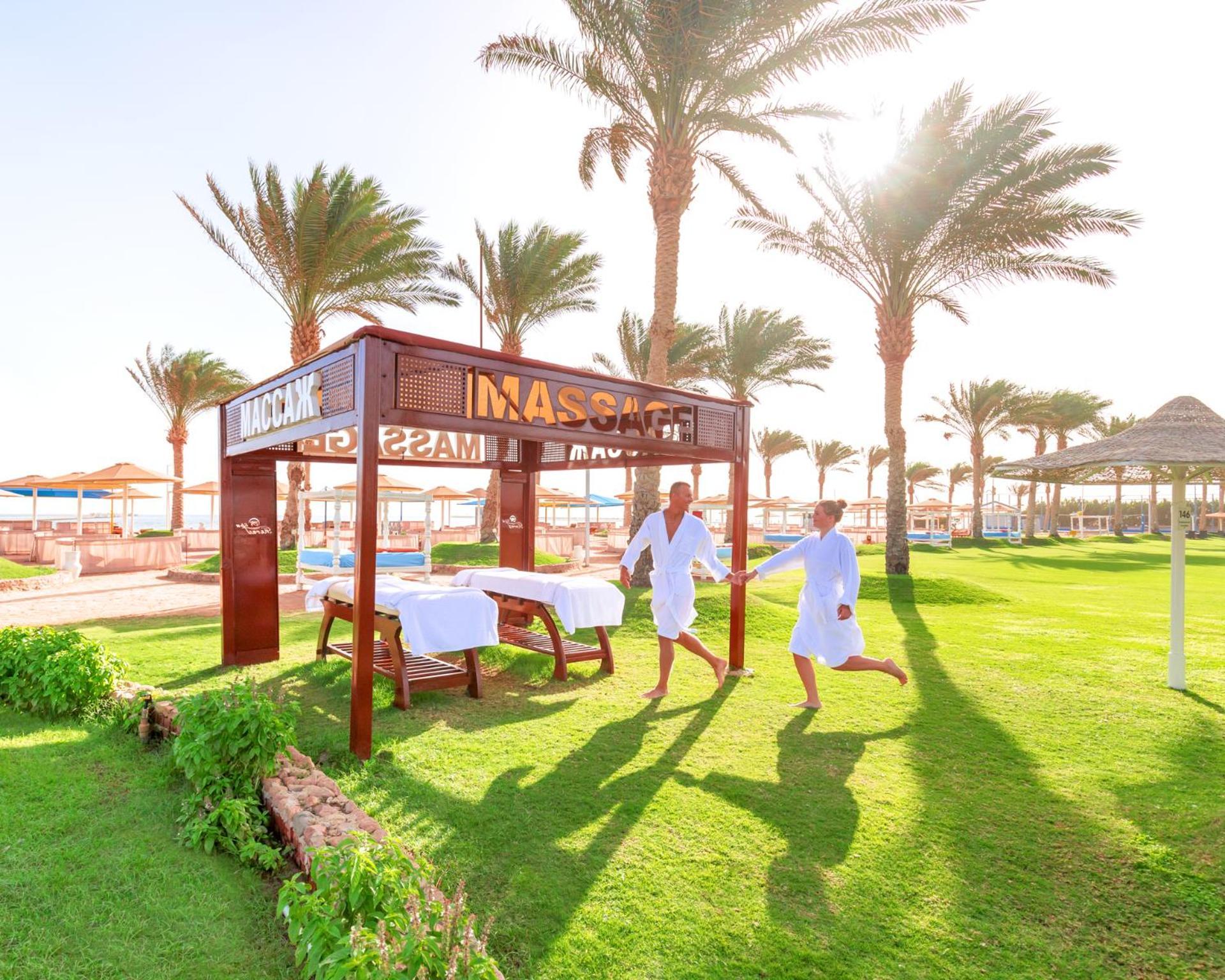 Hotel Royal Albatros Moderna - Families and couples only à Charm el-Cheikh Extérieur photo The photo shows a serene outdoor spa area, featuring a massage pavilion with a sign that reads "MASAGE." There are two individuals in white robes, appearing to enjoy a light-hearted moment while walking towards the pavilion. Surrounding the pavilion 